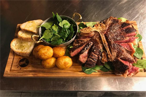 Tbone steak sliced served with mini biscuts, spinach, and bread slices
