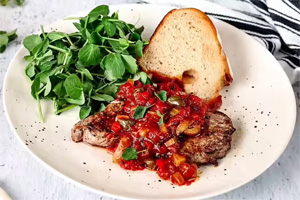 Steak topped with green olives in a chucky marinara sauce, served with spinach and bread