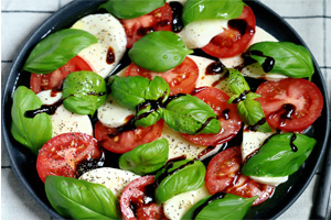Caprese salad with fresh mozzarella, ripe tomtoes, and basil topped with a balamic glaze 