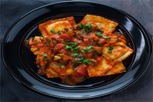 Raviolis mixed with marinara topped with tomatoes and green onions